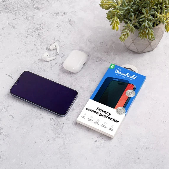 Ocushield Privacy Screen Protector packaging displayed next to smartphone, earbuds, and potted plant on concrete surface.
