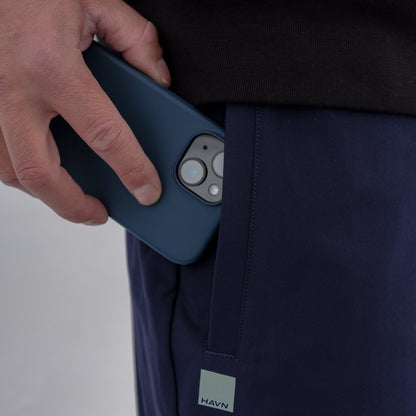 Hand holding navy HAVN WaveStopper™ Joggers with phone in pocket, showing functionality and fit.