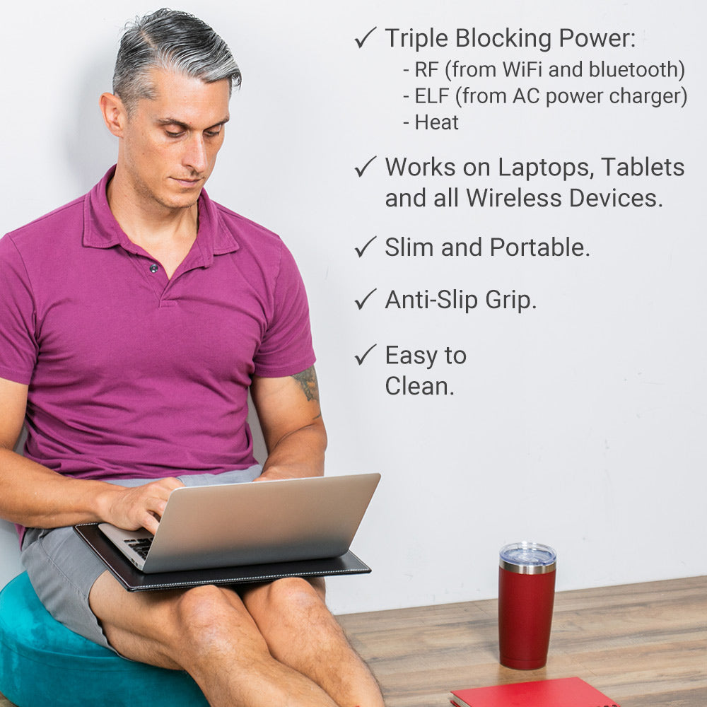 Man in magenta shirt using laptop on SYB Laptop Pad with product features listed: triple blocking power, wireless device compatibility, slim design, anti-slip grip, easy to clean.