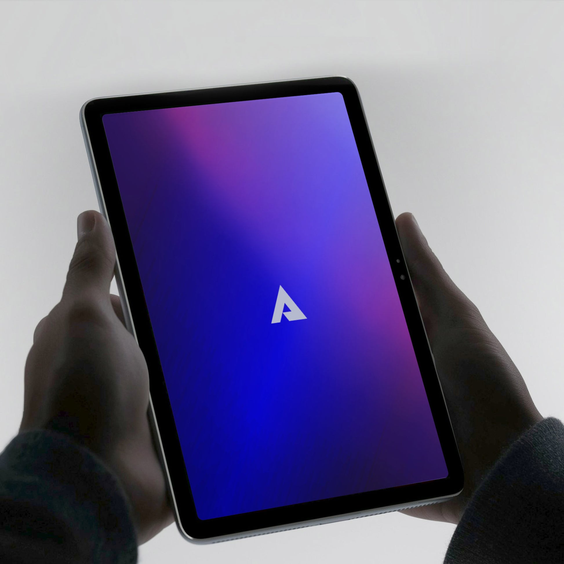 Hands holding Above Privacy & EMF-Free Tablet displaying purple gradient screen with white arrow logo.
