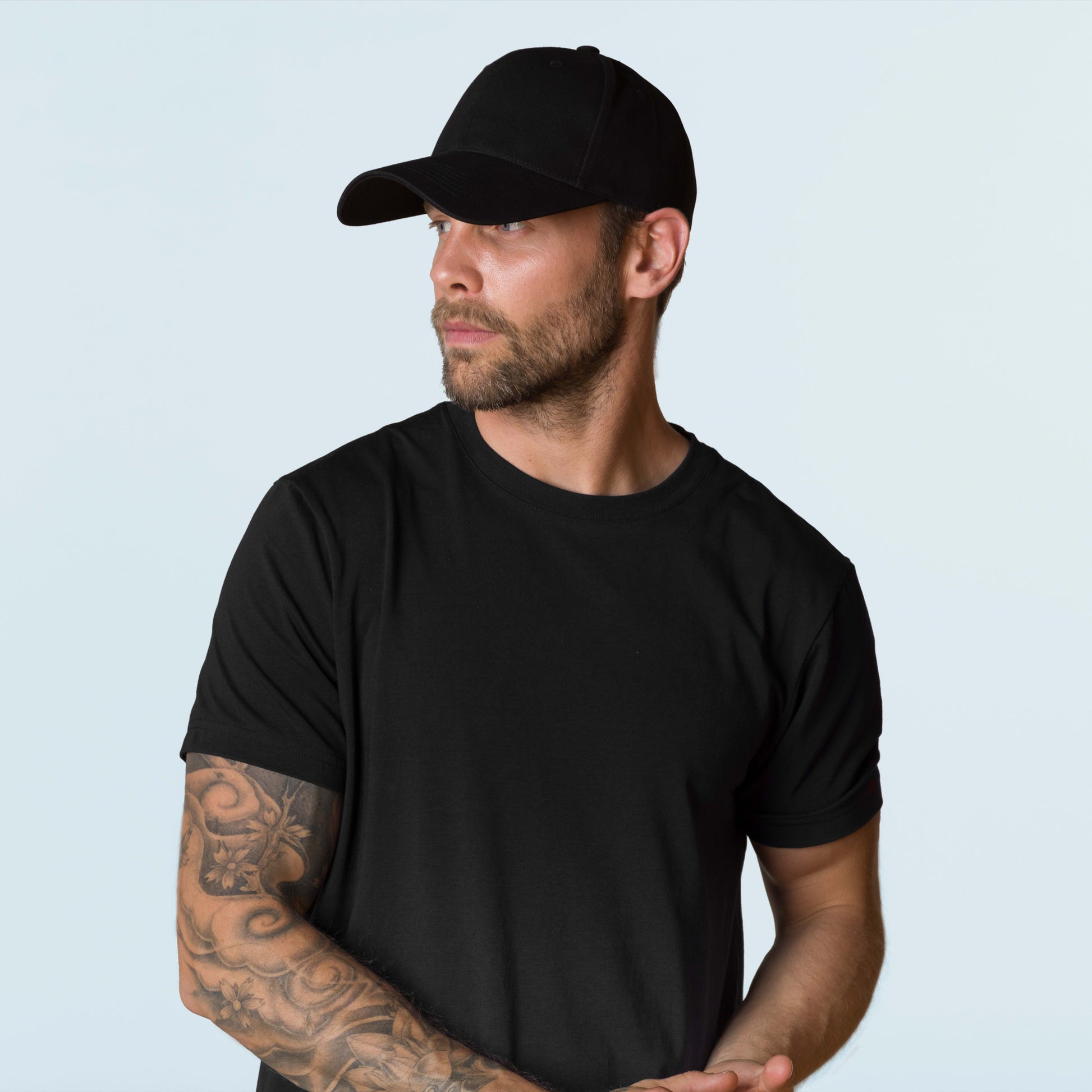 Man wearing black HAVN WaveStopper™ T-Shirt 2.0 and black cap, shown in side profile view against light background.