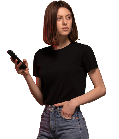 Woman wearing black HAVN WaveStopper™ T-Shirt 2.0 and jeans, holding a smartphone while looking to the side.