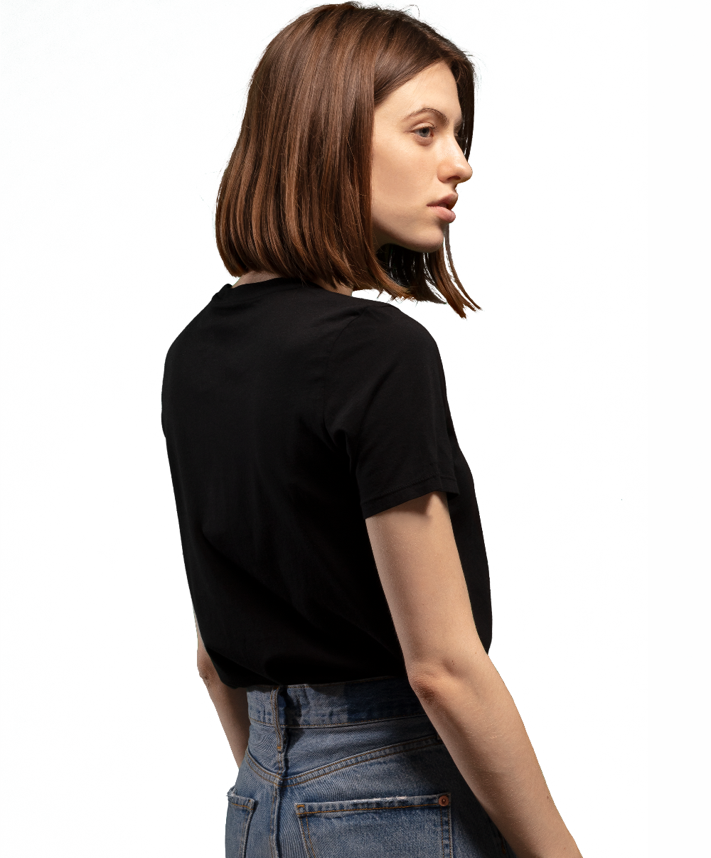 Woman wearing black HAVN WaveStopper™ T-Shirt 2.0 and blue jeans, shown from side profile view against white background.