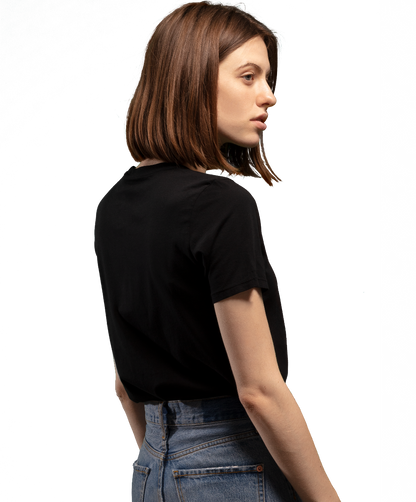 Woman wearing black HAVN WaveStopper™ T-Shirt 2.0 and blue jeans, shown from side profile view against white background.