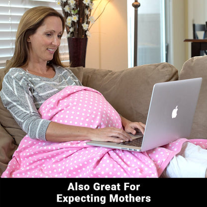Pregnant woman on couch using laptop while holding pink polka dot SYB Baby Blanket over her belly.