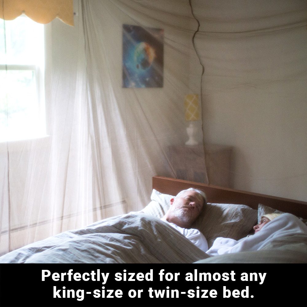 Man sleeping under sheer SYB Faraday Bed Canopy draped over bed with sunlight filtering through.