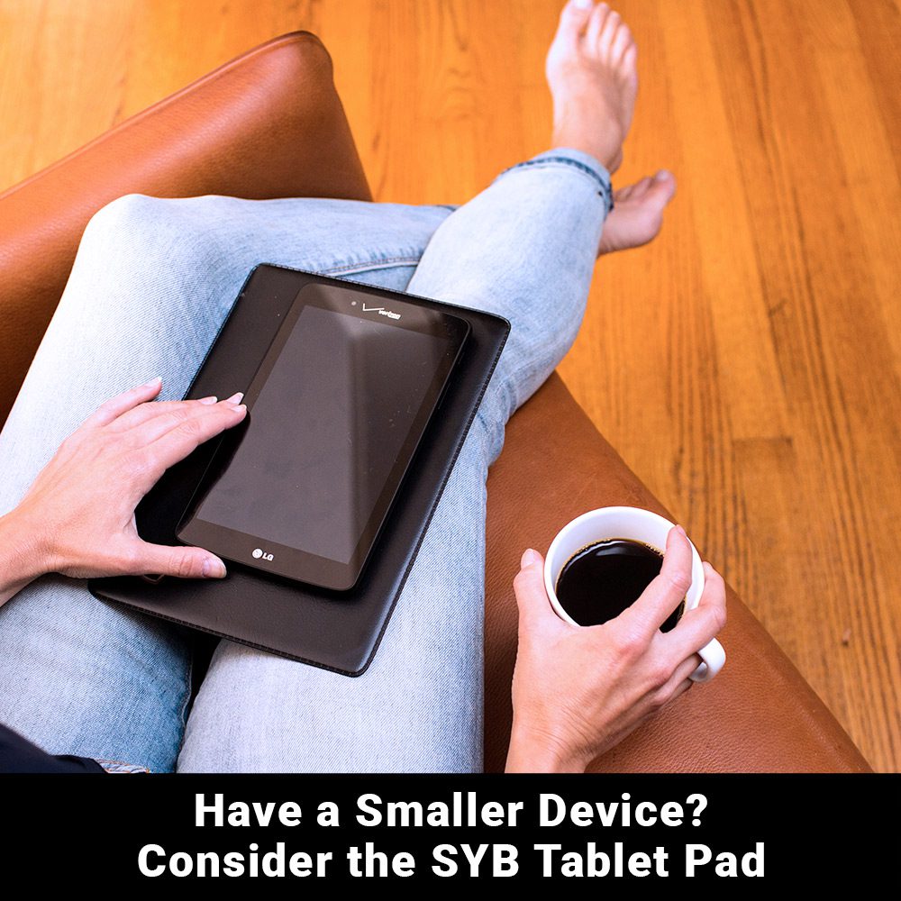 Person holding SYB Tablet Pad on lap with coffee cup, demonstrating size and portability for smaller devices.