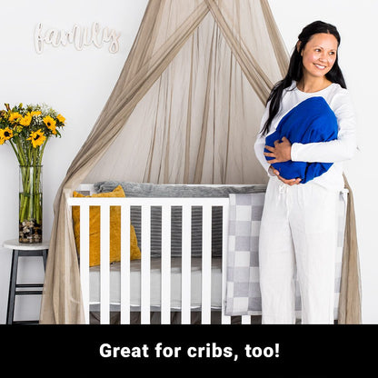 Pregnant woman holding blue pillow next to white crib with SYB Faraday Serenity Canopy draped overhead in nursery setting.