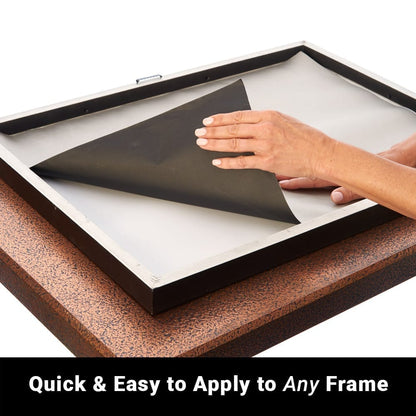 Hand peeling back black SYB Poster Frame Liner from white surface inside wooden frame to show easy application process.