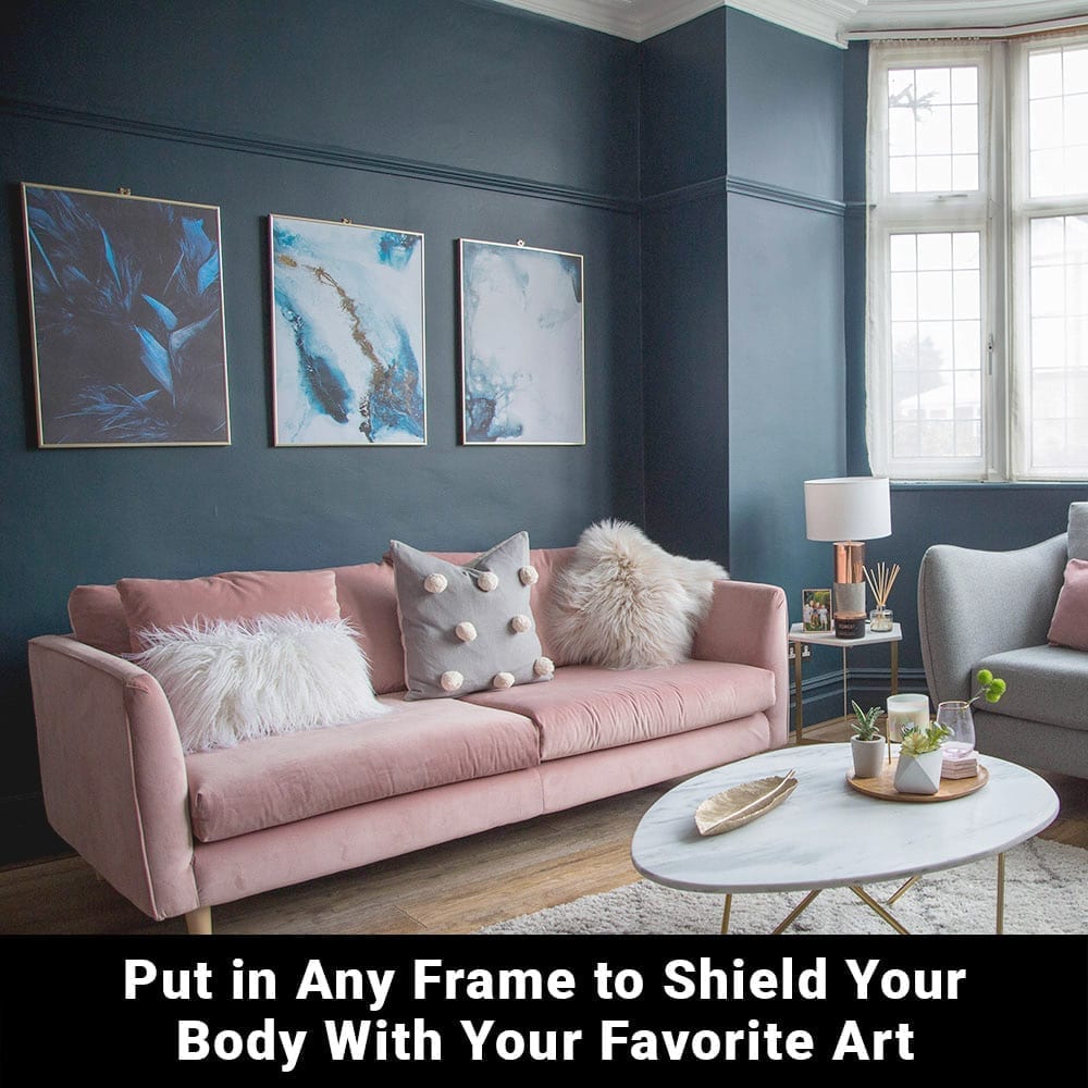 Modern living room with pink sofa and three framed blue artworks on dark teal wall above seating area.
