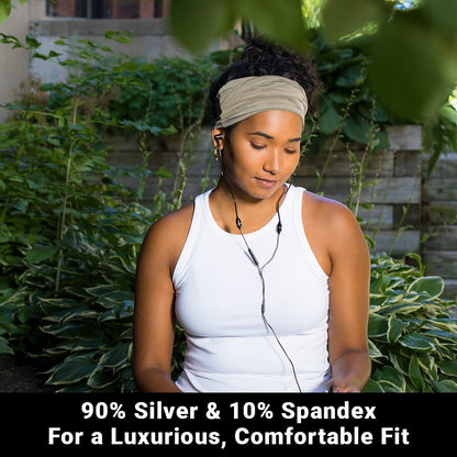 Woman wearing white SYB Neck Gaiter as headband in garden setting, showing fabric composition of 90% silver and 10% spandex.
