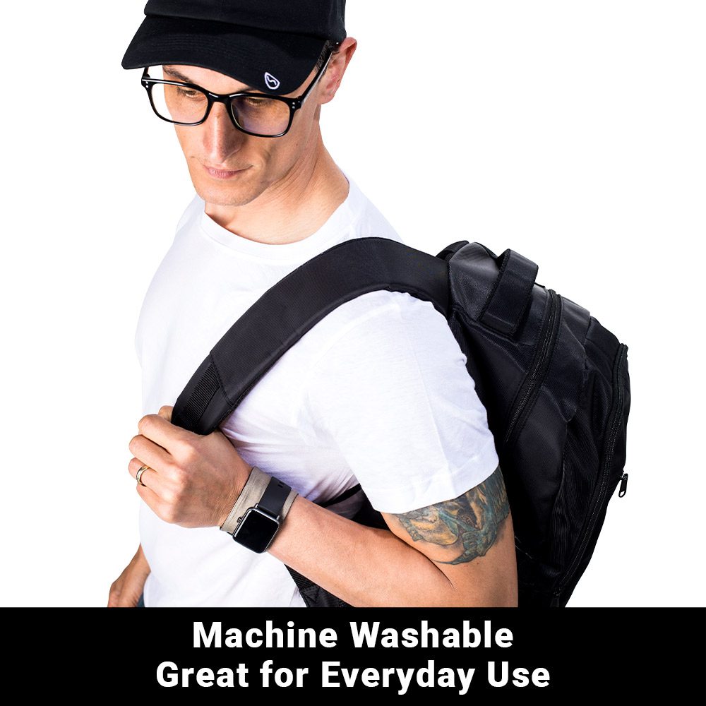 Man wearing black SYB Wrist Band on wrist while holding black backpack, displaying machine washable feature for everyday use.
